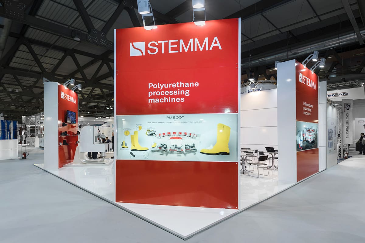 L'immagine raffigura un caso reale di allestimento fieristico: l'allestimento dello stand Stemma realizzato per fiera Simac Tanningh Tech di Milano. L'immagine mostra lo stand realizzato, ripreso esternamente dal lato Est.